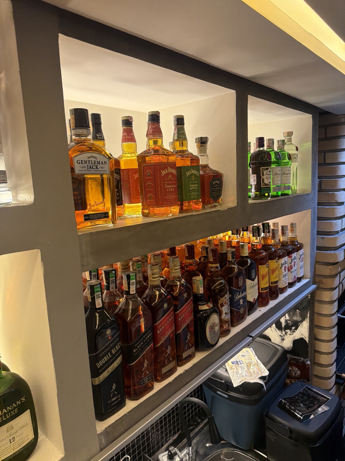 Bar do Espeto da Villa com bebidas expostas em nichos iluminados